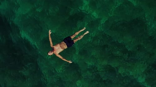 Vista aérea de un hombre flotando de espaldas en el mar.