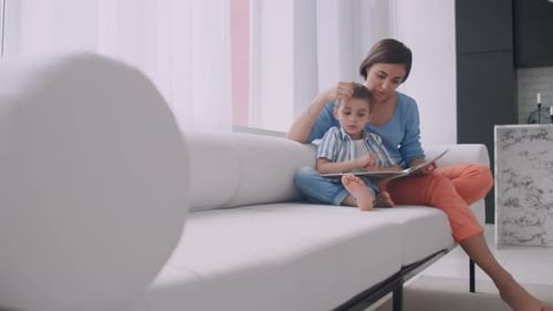 Mother and Child Reading a Book on Couch