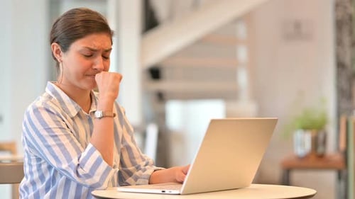 Sick Young Indian Woman with Laptop Coughing in Cafe