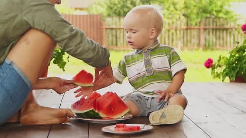 Blond Toddler Eating Watermelon with Adult on Deck