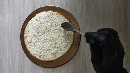 Gloved Hand Moistening Cake with Spoon