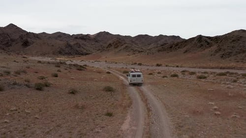 Car Goes on a Dirt Road Among the Mountains