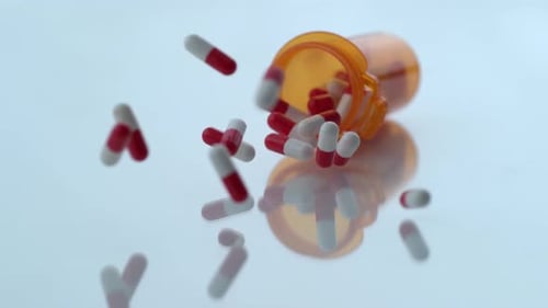 Pills Spilling From Prescription Bottle on Table