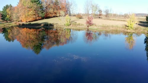Aerial Drone Shot Ascending to Reveal a Pristine Farm Pond with Fall Colors