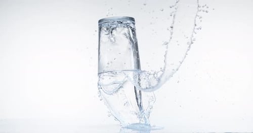 Caída de vidrio y salpicaduras de agua contra fondo blanco, cámara lenta 4K