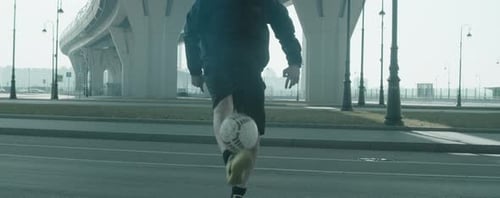 Männlicher Fußballspieler jongliert Ball auf der Straße