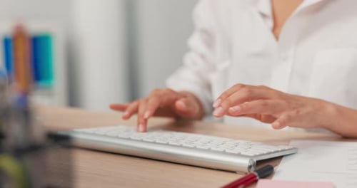 Nahaufnahme der Tastatur vom Computer, der auf einem Holzschreibtisch steht, berufstätige Frau im weißen Hemd jung