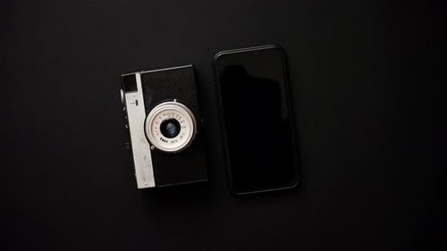Old Retro Film Camera and Modern Smartphone on Black Background