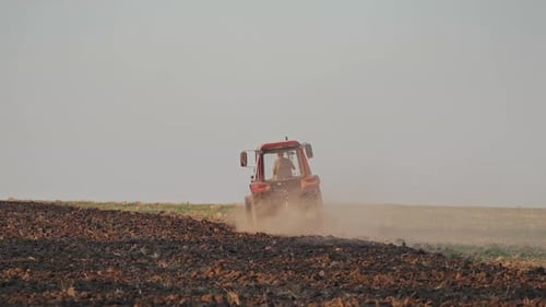 Tractor working on large field. Farmer in tractor preparing land with seedbed cultivator