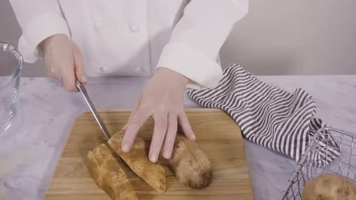 Chef cuts potatoes on wooden cutting board