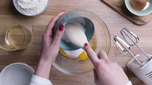 Female Hands Pour Sugar with Wooden Spoon into Bowl. - Top Down Shot