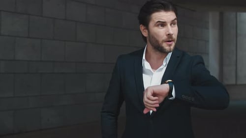 Worried Business Man Checking Time on Wristwatch in Modern City