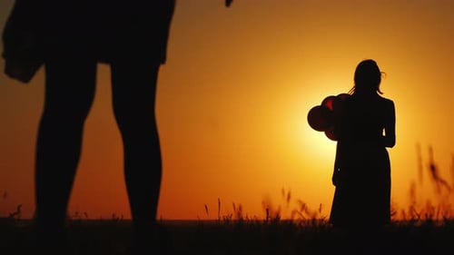 Sunset Silhouette of Child, Woman with Balloons Walking