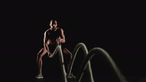 Muscular Man Vigorously Working Out With Ropes
