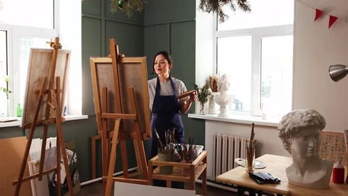 Art Studio Young Woman Puts a Canvas on an Easel Picks Up a Palette and Starts Painting