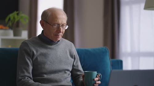 Senior Man Video Calling On Laptop At Home