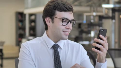 Excited Young Man Celebrates on Phone in Office