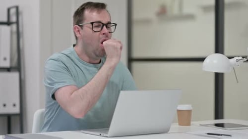 Man Coughing While Working at Computer in Office