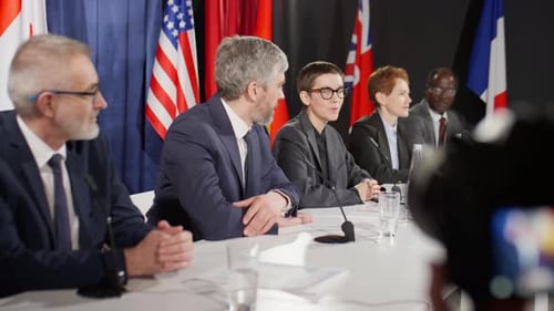Serious People at Press Conference with Flags