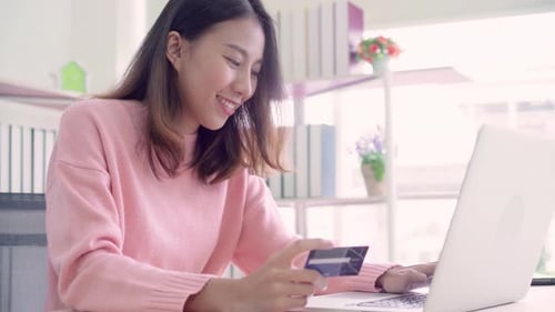 Asian woman using computer or laptop buying online shopping by credit card while wear sweater