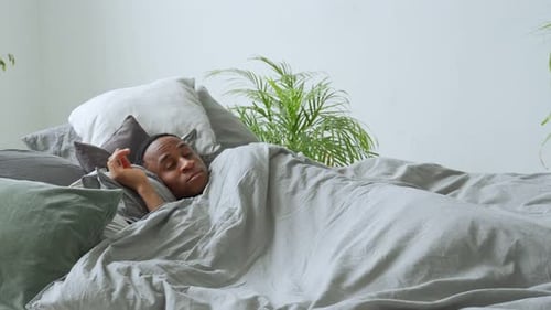 Man Wakes Up and Stretches in Bed