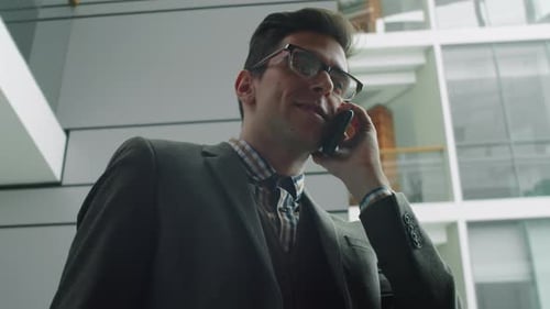 Young Adult Talking on Phone in Office Lobby