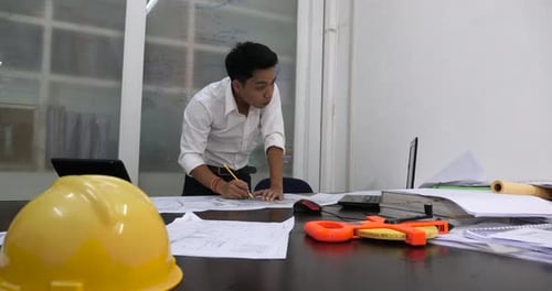 Male Architect Working With Blueprints In The Office