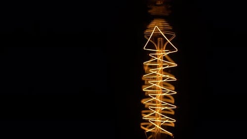 Light Bulb with Geometric Filament Glowing on Black