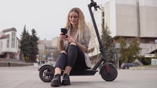 Woman Using Phone While Sitting on Scooter