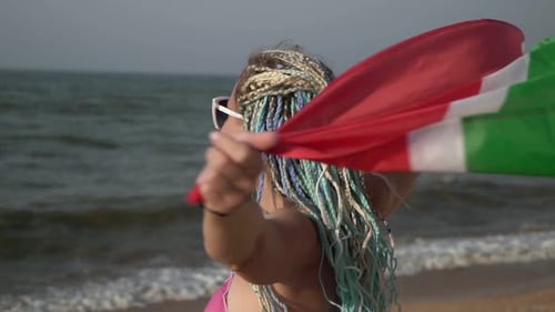 Schöne Frau mit südafrikanischer Flagge am Meeresstrand in Zeitlupe
