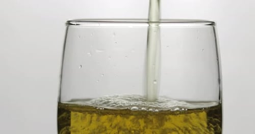 Pouring Cold Golden Light Beer Into a Glass. Craft Beer Making Bubbles and Foam