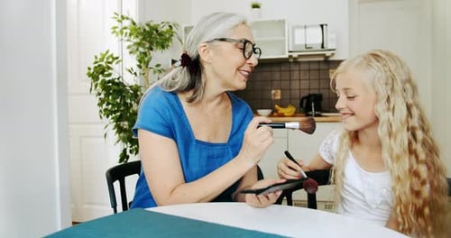 Grandmother Applying Makeup to Happy Young Girl at Home