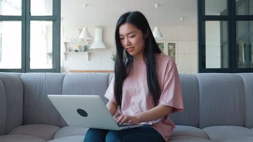 Smiling Woman Using Laptop on Sofa in Living Room