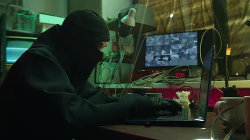 Hacker Wearing Balaclava Stealing Information From Laptop Breaking Password and Looking Around