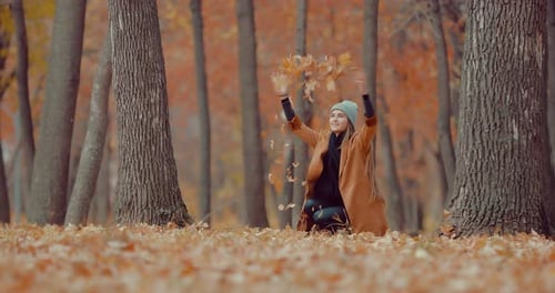 Beautiful Girl in the Autumn Forest Throws Up Autumn Foliage