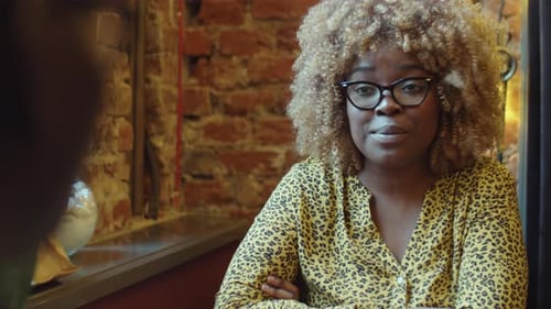 Afroamerikanerin im Gespräch mit Kollegin im Café