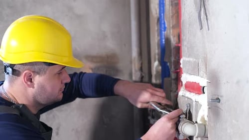 Construction Worker Tightening Pipe With Wrench