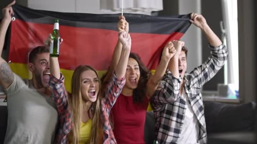 Friends Cheering With Flags Indoors at a Home Party
