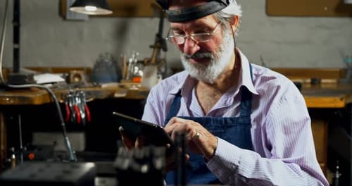 Goldsmith using digital tablet in workshop