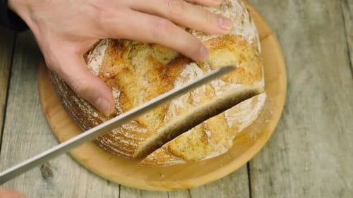 A Man is Cutting Bread on the Table