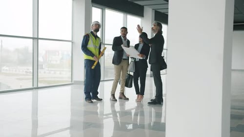 Gruppe männlicher und weiblicher Ingenieure diskutieren über den Entwurf für die Innenüberprüfung eines neuen Gebäudes