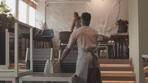 Waiter Arranging Chairs in Coffee Shop