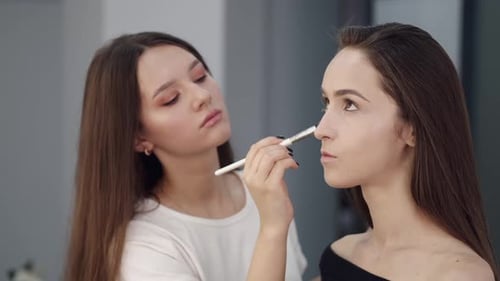 Woman Applying Makeup to Another Woman in Studio