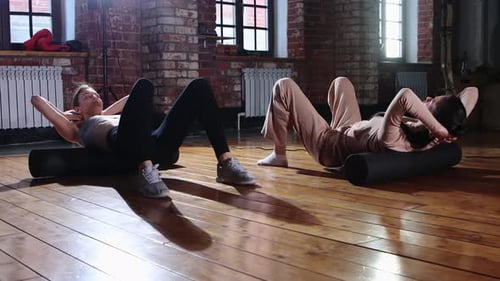 Sports Women Training Together in the Gym Doing Exercises for Her Back Using a Soft Roller