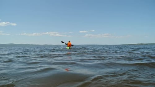 Man Kayaking in Calm Lake Water on Sunny Day