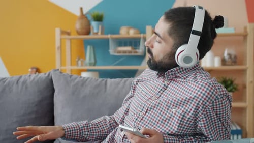 Man Listens to Music on Headphones Indoors