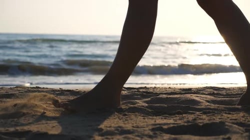 Close Up of Female Feet Walking on Golden Sand at the Beach with Ocean Waves at Background