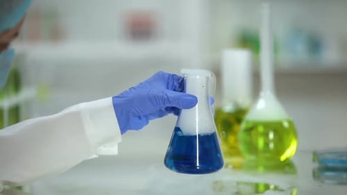 Lab Worker Holding Beaker With Steaming Blue Liquid