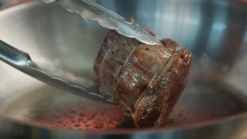 Close-up of a filet mignon being cooked in a frying pan