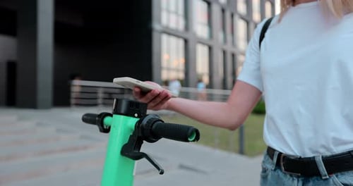 Close up of woman rents electric scooter using mobile phone app.